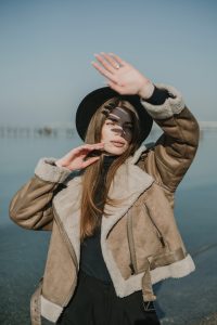 Devushka-v-chernoj-shljapke-prikryvaet-glaza-ot-solnca Девушка в черной шляпке прикрывает глаза от солнца