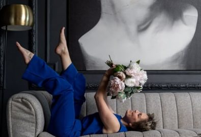 женщина в синем костюме с букетом цветов лежит на диване